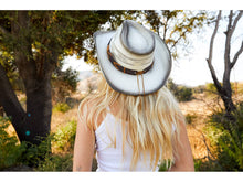 Load image into Gallery viewer, Woman wearing a white straw cowboy hat with a brown band facing behind.

